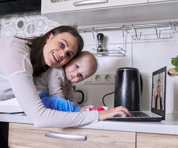 Young mother with toddler in her arms talking online with psychologist, making video call, video conference using laptop at home. Technology, mental health, therapy, distance lifestyle concept